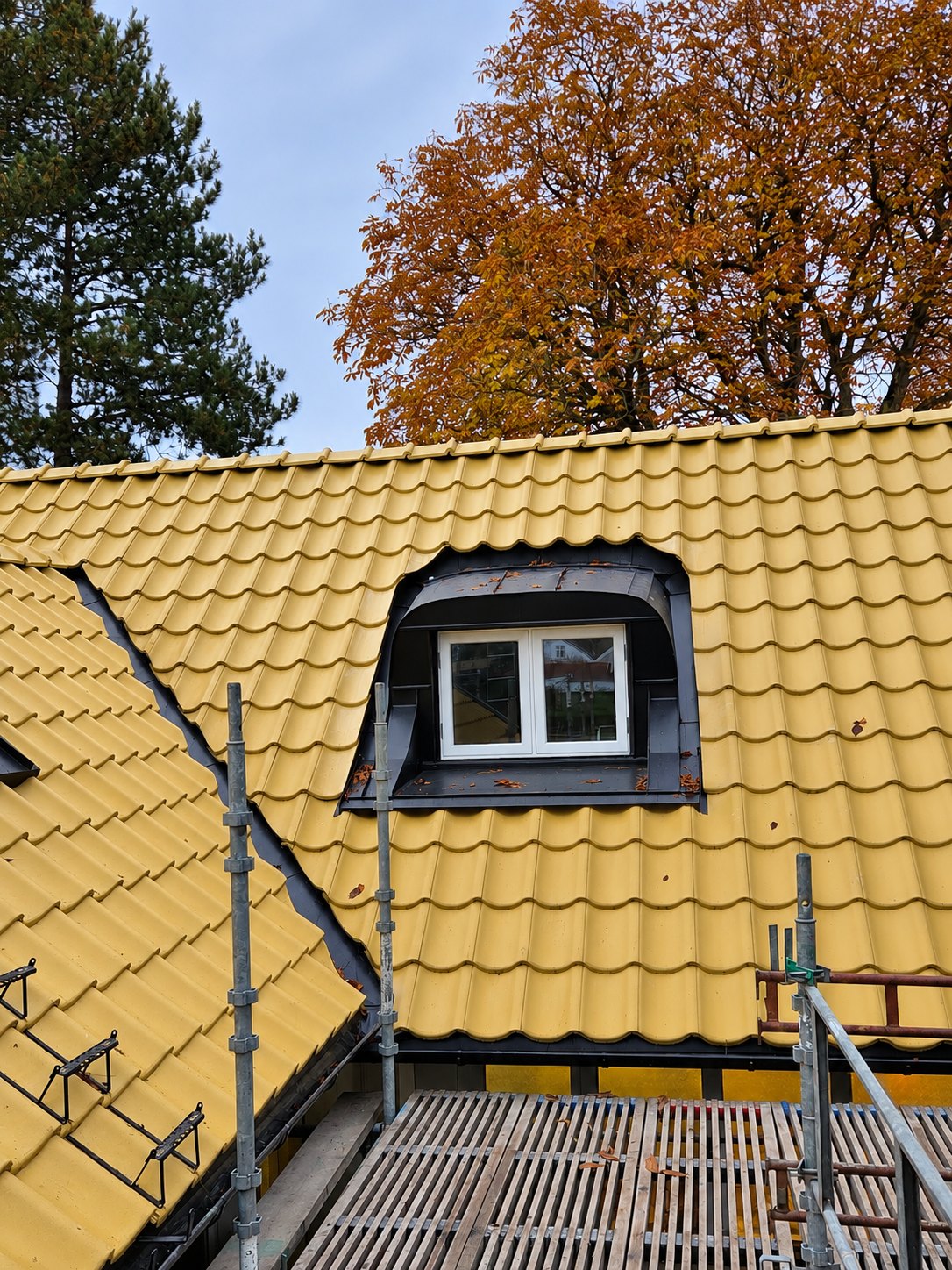 Svart välvd takkupa i plåt på gult tegeltak